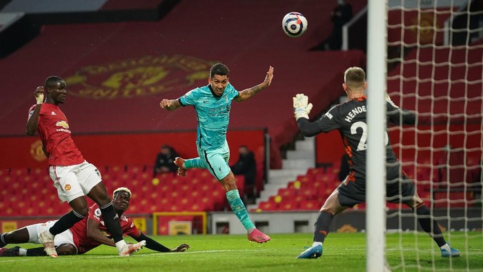 MANCHESTER, ENGLAND - MAY 13: Roberto Firmino of Liverpool scores their sides second goal past Dean Henderson of Manchester United during the Premier League match between Manchester United and Liverpool at Old Trafford on May 13, 2021 in Manchester, England. Sporting stadiums around the UK remain under strict restrictions due to the Coronavirus Pandemic as Government social distancing laws prohibit fans inside venues resulting in games being played behind closed doors. (Photo by Dave Thompson - Pool/Getty Images)