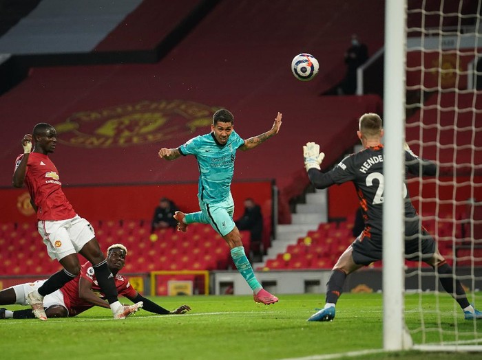 MANCHESTER, ENGLAND - MAY 13: Roberto Firmino of Liverpool scores their side's second goal past Dean Henderson of Manchester United during the Premier League match between Manchester United and Liverpool at Old Trafford on May 13, 2021 in Manchester, England. Sporting stadiums around the UK remain under strict restrictions due to the Coronavirus Pandemic as Government social distancing laws prohibit fans inside venues resulting in games being played behind closed doors. (Photo by Dave Thompson - Pool/Getty Images)