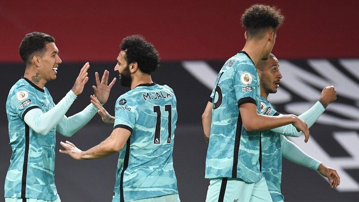 Liverpools Roberto Firmino, left, celebrates with Liverpools Mohamed Salah after scoring his sides third goal during the English Premier League soccer match between Manchester United and Liverpool, at the Old Trafford stadium in Manchester, England, Thursday, May 13, 2021. (Peter Powell/Pool via AP)