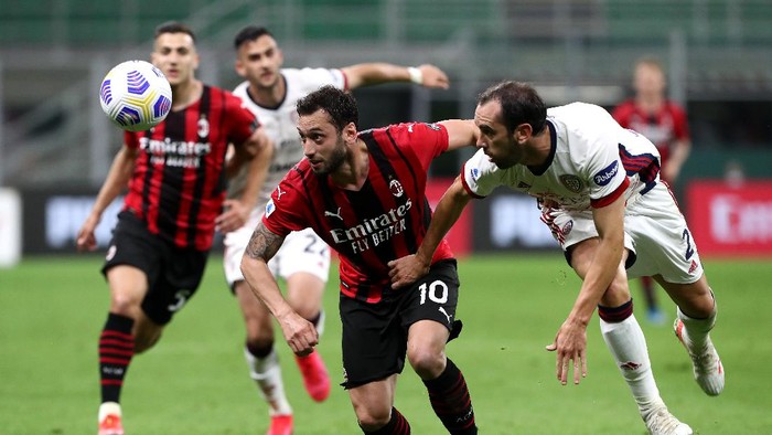MILAN, ITALY - MAY 16: Hakan Calhanoglu of AC Milan battles for possession with Diego Godin of Cagliari Calcio during the Serie A match between AC Milan  and Cagliari Calcio at Stadio Giuseppe Meazza on May 16, 2021 in Milan, Italy. Sporting stadiums around Italy remain under strict restrictions due to the Coronavirus Pandemic as Government social distancing laws prohibit fans inside venues resulting in games being played behind closed doors. (Photo by Marco Luzzani/Getty Images)
