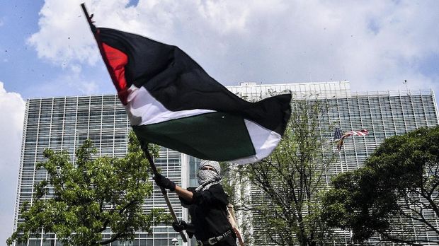 Seorang massa aksi mengimbarkan bendera Palestina saat mengikuti aksi solidaritas dukung Palestina terkait kekerasan yang terjadi beberapa waktu lalu oleh Israel di depan Kedubes AS, Jakarta, Selasa (18/5/2021). Mereka dalam aksinya mengajak masyarakat Indonesia untuk terus mendukung dan membantu Palestina atas serangan yang dilancarkan Israel serta meminta pemerintah Indonesia mampu berkampanye dukung Palestina di depan PBB. ANTARA FOTO/Muhammad Adimaja/hp.