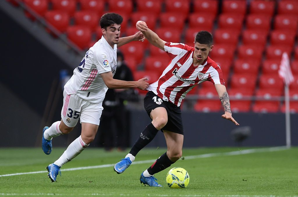 BILBAO, SPAIN - MAY 16: Oihan Sancet of Athletic Club is challenged by Miguel Gutierrez of Real Madrid during the La Liga Santander match between Athletic Club and Real Madrid at Estadio de San Mames on May 16, 2021 in Bilbao, Spain. Sporting stadiums around Spain remain under strict restrictions due to the Coronavirus Pandemic as Government social distancing laws prohibit fans inside venues resulting in games being played behind closed doors.  (Photo by Juan Manuel Serrano Arce/Getty Images)
