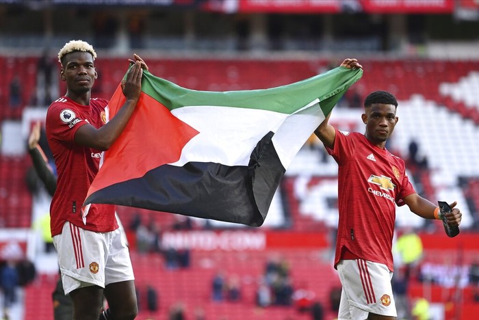 Manchester Uniteds Paul Pogba, left, and Manchester Uniteds Amad Diallo hold up the flag of Palestine after the English Premier League soccer match between Manchester United and Fulham at Old Trafford stadium in Manchester, England, Tuesday, May 18, 2021. (AP Photo/Laurence Griffiths, Pool)