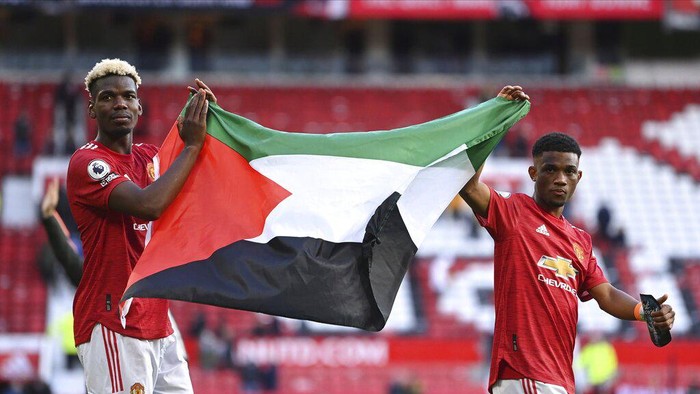 Manchester Uniteds Paul Pogba, left, and Manchester Uniteds Amad Diallo hold up the flag of Palestine after the English Premier League soccer match between Manchester United and Fulham at Old Trafford stadium in Manchester, England, Tuesday, May 18, 2021. (AP Photo/Laurence Griffiths, Pool)