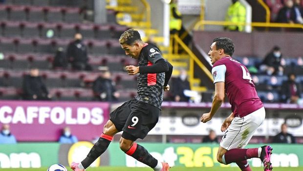 Liverpool's Roberto Firmino, left, scores the opening goal during the English Premier League soccer match between Burnley and Liverpool at Turf Moor in Burnley, England, Wednesday May 19, 2021. (Clive Mason/Pool via AP)