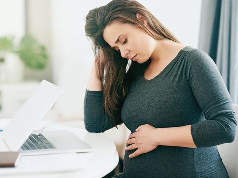 Shot of a young pregnant woman feeling unwell while working from home