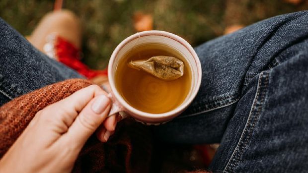 Woman drinking tea outdoors in autumn casual clothing close up of ceramic tea cup 
Photo taken outdoors in nature in sunlight