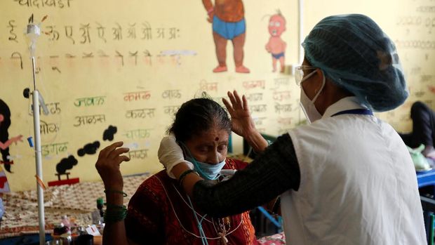 A nurse helps a woman suffering from coronavirus disease (COVID-19) wear an oxygen tube inside a classroom turned COVID-19 care facility on the outskirts of Mumbai, India, May 24, 2021. REUTERS/Francis Mascarenhas