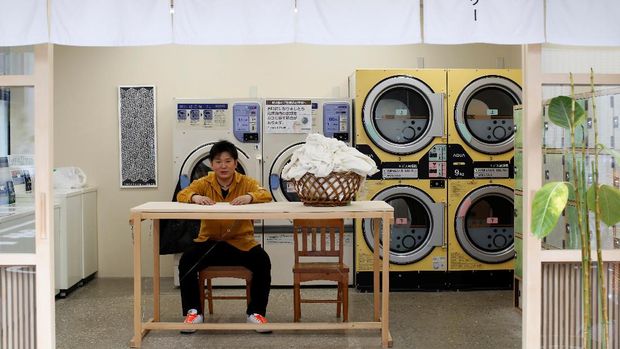 Akihiro Takahashi, 34, an owner and chef of a Japanese restaurant, poses for a portrait while visiting Koganeyu Coin Laundry, a laundrette in Tokyo, Japan, May 7, 2021. Takahashi would like the Games to take place but not this year. He worries about the health risks from foreign athletes and officials entering Japan, and mourns the overseas tourists who would have packed his Japanese restaurant in a usual Olympics year. 