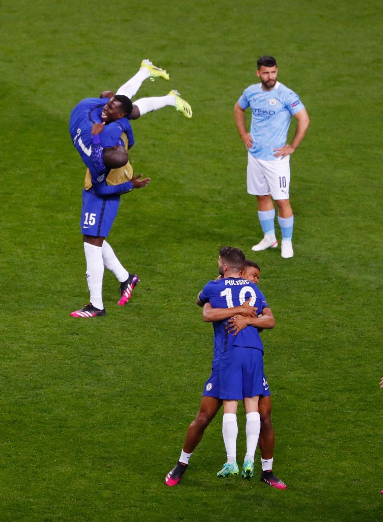 PORTO, PORTUGAL - MAY 29: Kurt Zouma, Ngolo Kante and teammates of Chelsea celebrate victory as Sergio Aguero of Manchester City looks dejected following the UEFA Champions League Final between Manchester City and Chelsea FC at Estadio do Dragao on May 29, 2021 in Porto, Portugal. (Photo by Susan Vera - Pool/Getty Images)