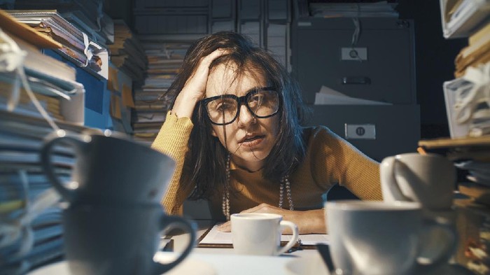 overwork Stressed exhausted woman sitting at office desk and working overtime, she is overloaded with work