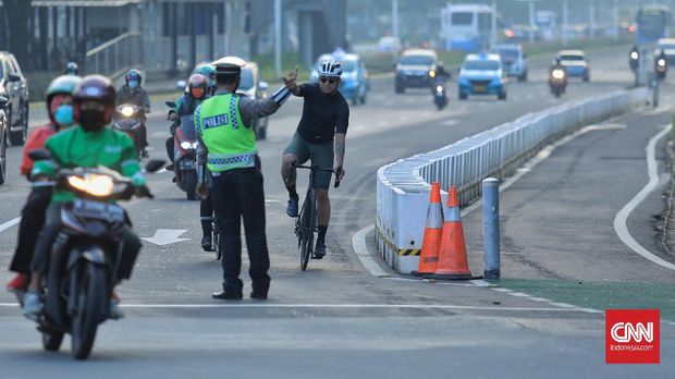(CNN Indonesia/ Adi Maulana) Petugas kepolisian menghalau setiap sepeda yang berada di luar jalur di kawasan Sudirman - Thamrin, Jakarta Pusat, Rabu (2/5/2021). Wakil Gubernur DKI Jakarta Ahmad Riza Patria mengatakan, sepeda road bike diperbolehkan untuk melintas di Jalan Sudirman-Thamrin pada hari kerja Senin-Jumat. Namun, izin melintas dibatasi dari pukul 05.00-06.30 WIB untuk hari Senin-Jumat. (CNN Indonesia/ Adi Maulana)