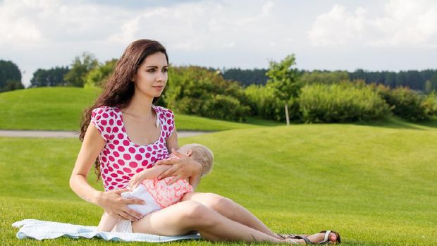 Young woman breastfeeding her baby outdoors