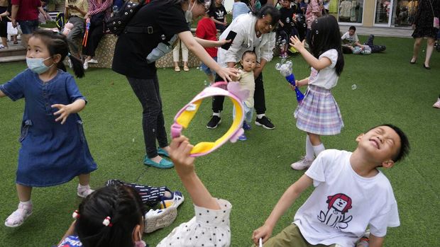 A child holds a dinosaur balloon during Children's Day at a mall in Beijing on Tuesday, June 1, 2021. China's ruling Communist Party said it will ease birth limits to allow all couples to have three children instead of two in hopes of slowing the rapid aging of its population, which is adding to strains on the economy and society. (AP Photo/Ng Han Guan)