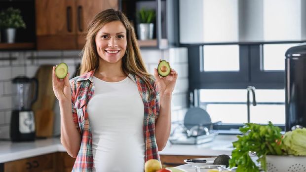 Young beautiful pregnant woman preparing healthy meal with fruites and vegetables