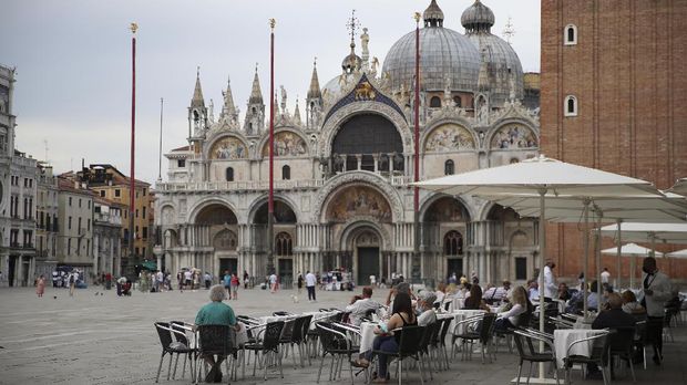 People sit at a restaurant in St. Mark's Square, as the region of Veneto becomes a 