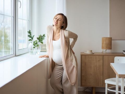 Healthcare, treatment. Young pregnant woman feeling sudden pain in her back. Future mom suffering from backpain. High quality photo