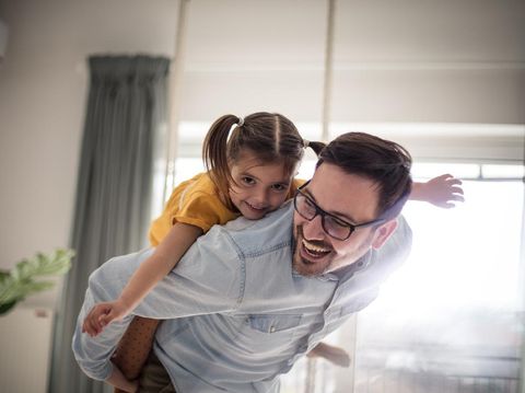 A dad helps his little girl go skateboarding, holding her waist for support.  Shot in Los Angeles, California by the Santa Monica Pier.