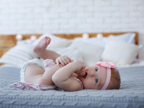 The newborn was wrapped in a green cloth and was placed on a soft rubber mat with a blurred background.