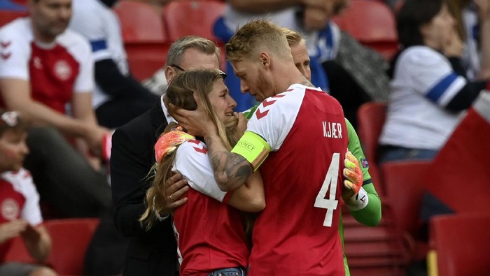 Denmarks team captain Simon Kjaer right, talks to a woman wearing a team jersey of Denmarks Christian Eriksen who was taken away from the field on a stretcher after collapsing on the pitch during the Euro 2020 soccer championship group B match between Denmark and Finland at Parken Stadium in Copenhagen, Saturday, June 12, 2021. (Stuart Franklin/Pool via AP)