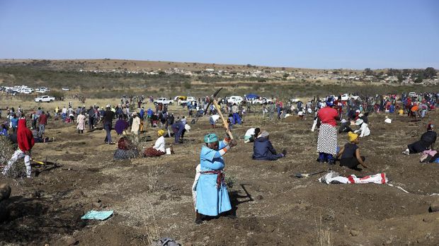 A woman uses a pickaxe to dig as fortune seekers flock to the village after pictures and videos were shared on social media showing people celebrating after finding what they believe to be diamonds, in the village of KwaHlathi outside Ladysmith, in KwaZulu-Natal province, South Africa, June 14, 2021. REUTERS/Siphiwe Sibeko