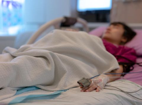 Asian female patient warded and laying on the bed connected to multiple medical devices