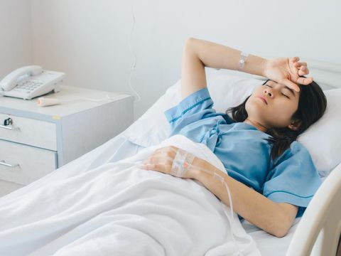 Asian female patient warded and laying on the bed connected to multiple medical devices