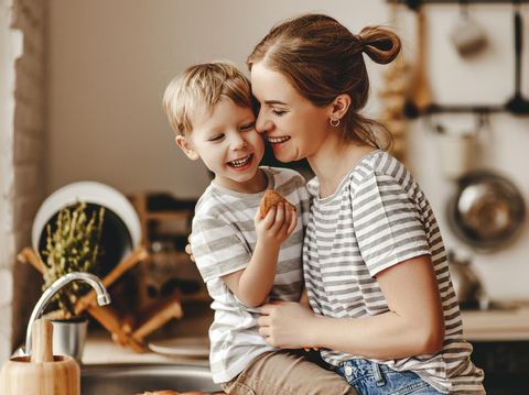 preparation of a family breakfast. mother and child son cut bread and eat cookies with milk in morning