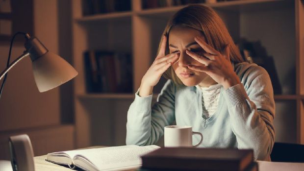 Tired student is learning at home. She is rubbing her eyes.