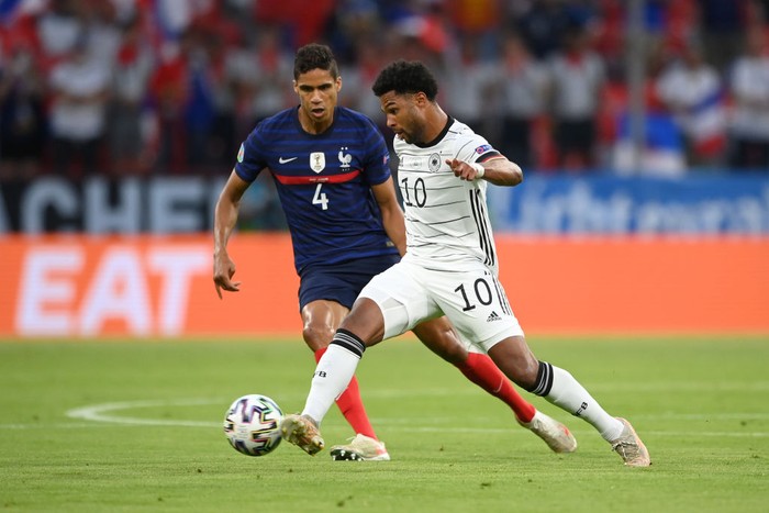 MUNICH, GERMANY - JUNE 15: Serge Gnabry of Germany is closed down by Raphael Varane of France during the UEFA Euro 2020 Championship Group F match between France and Germany at Football Arena Munich on June 15, 2021 in Munich, Germany. (Photo by Matthias Hangst/Getty Images)