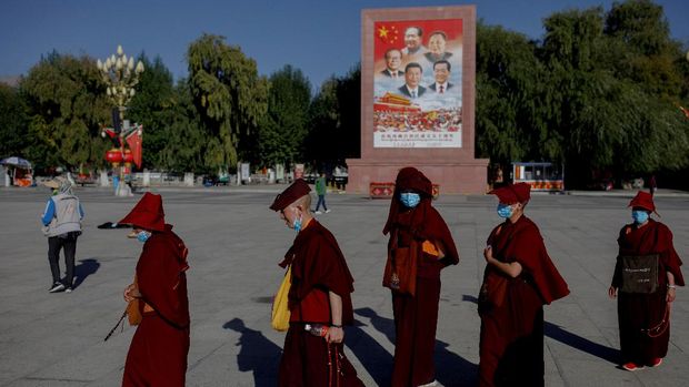 Buddhist nuns walk past a poster showing Chinese President Xi Jinping and former leaders Jiang Zemin, Mao Zedong, Deng Xiaoping and Hu Jintao in Lhasa during a government-organised tour of the Tibet Autonomous Region, China, October 15, 2020.  Picture taken October 15, 2020.  REUTERS/Thomas Peter  REFILE - CORRECTING FAMILY NAMES