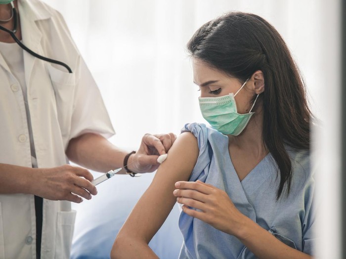 Doctor giving patient vaccine, flu or influenza shot or taking blood test with needle. Nurse with injection or syringe. Cropped image of handsome mature doctor in protective gloves making woman an injection