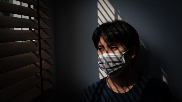 Quarantine of risky people to prevent  COVID-19 spreading, Man wearing mask and looking out on the window at home, Corona virus. COVID-19 and epidemic virus symptoms and protection. Coronavirus and Air pollution pm2.5 concept.