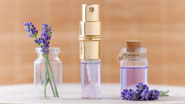 lavender water in glass bottles and fresh lavender flowers for relax on brown background, selective focus