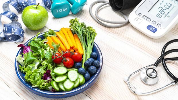 Ilustrasi diet hipertensi Healthy lifestyle concept: dumbbells, tape measure, salad plate, digital blood pressure monitor and doctor stethoscope shot on white table. High resolution 42Mp studio digital capture taken with SONY A7rII and Zeiss Batis 40mm F2.0 CF lens