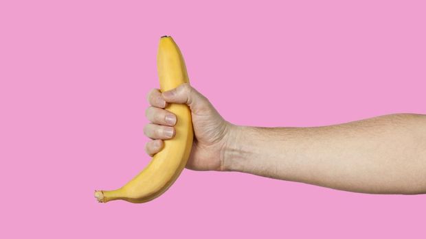 Banana as a symbol of male penis in hand on a yellow background hidden by censorship. Sexual masturbation and orgasm, impotence problem. Self-pleasure concept.