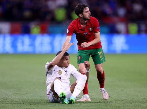 BUDAPEST, HUNGARY - JUNE 23: Kylian Mbappe of France is helped up by Bernardo Silva of Portugal during the UEFA Euro 2020 Championship Group F match between Portugal and France at Puskas Arena on June 23, 2021 in Budapest, Hungary. (Photo by Alex Pantling/Getty Images)