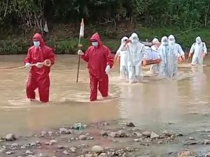 Petugas Pakai APD Panggul Jenazah Lewati Sungai-Persawahan