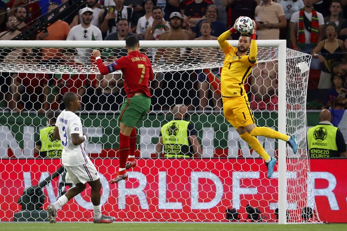 France's goalkeeper Hugo Lloris jumps for the ball in front of Portugal's Cristiano Ronaldo, center, during the Euro 2020 soccer championship group F match between Portugal and France at the Puskas Arena in Budapest, Wednesday, June 23, 2021. (Bernadett Szabo, Pool photo via AP)