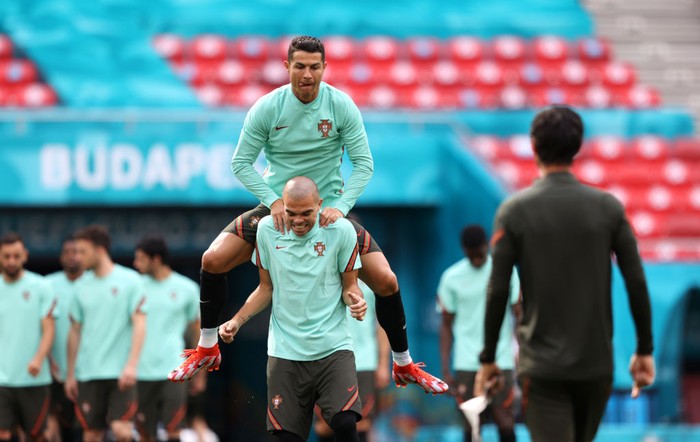 Cristiano Ronaldo BUDAPEST, HUNGARY - JUNE 14: Cristiano Ronaldo of Portugal jumps on the back of team mate Pepe during the Portugal Training Session ahead of the UEFA Euro 2020 Group F match between Hungary and Portugal at Puskas Arena on June 14, 2021 in Budapest, Hungary. (Photo by Alex Pantling/Getty Images)