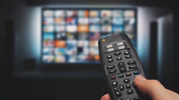 VOD service on television. Man watching TV, streaming service, video on demand, remote control in hand.