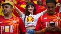 Suporter cantik dari Macedonia Utara memberikan semangat kepada para pemain dengan membentangkan bendera negaranya. AP Photo/Vadim Ghirda, Pool.