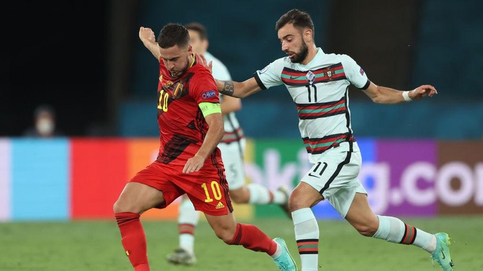SEVILLE, SPAIN - JUNE 27: Eden Hazard of Belgium makes a pass as he is tackled by Bruno Fernandes of Portugal during the UEFA Euro 2020 Championship Round of 16 match between Belgium and Portugal at Estadio La Cartuja on June 27, 2021 in Seville, Spain. (Photo by Alexander Hassenstein/Getty Images)