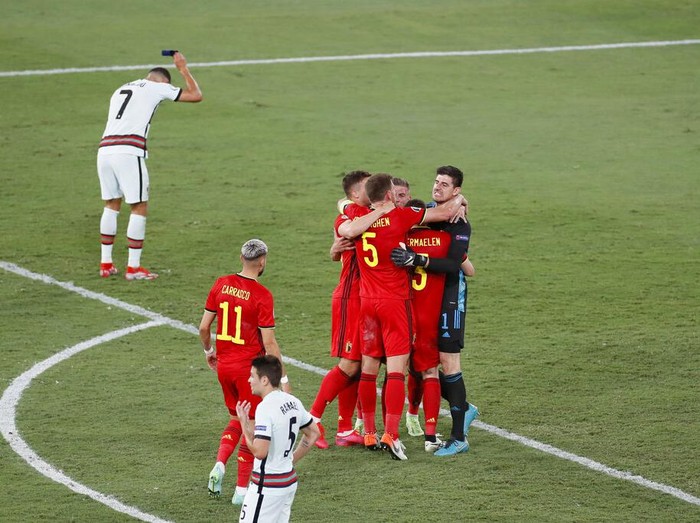 Belgium players celebrate winning 1-0 as Portugal's Cristiano Ronaldo, 7, reacts after the Euro 2020 soccer championship round of 16 match between Belgium and Portugal at La Cartuja stadium in Seville, Spain, Sunday, June 27, 2021. (Jose Manuel Vidal/Pool via AP)