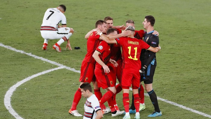 Belgium players celebrate winning 1-0 as Portugal's Cristiano Ronaldo, 7, reacts after the Euro 2020 soccer championship round of 16 match between Belgium and Portugal at La Cartuja stadium in Seville, Spain, Sunday, June 27, 2021. (Jose Manuel Vidal/Pool via AP)
