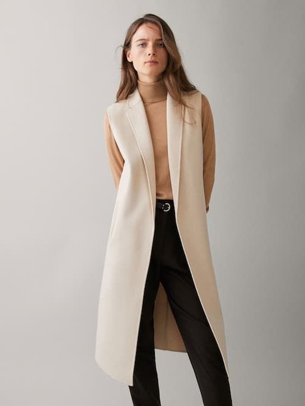 Memadukan turtleneck dan cardigan tanpa lengan.