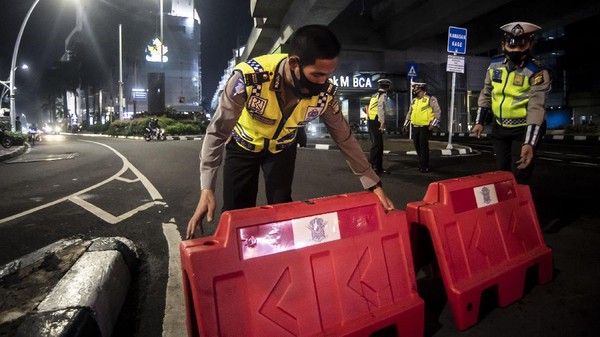 PEMBATASAN MOBILITAS WARGA DI JAKARTA Petugas kepolisian menyusun pembatas jalan saat akan melakukan penutupan jalan dalam rangka pembatasan mobilitas warga guna menekan penyebaran COVID-19 di kawasan Bulungan, Jakarta, Senin (21/6/2021). Pembatasan tersebut dilakukan mulai pukul 21.00 WIB hingga 04.00 WIB di 10 titik di Kota Jakarta diantaranya Jalan Cikini Raya, kawasan Jalan Sabang, kawasan BKT, kawasan Kemang, PIK 2, kawasan Kota Tua dan Bulungan. ANTARA FOTO/Muhammad Adimaja/wsj.