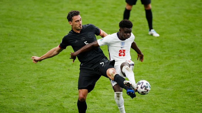 Timnas Inggris, Timnas Jerman LONDON, ENGLAND - JUNE 29: Bukayo Saka of England is challenged by Mats Hummels of Germany during the UEFA Euro 2020 Championship Round of 16 match between England and Germany at Wembley Stadium on June 29, 2021 in London, England. (Photo by John Sibley - Pool/Getty Images)