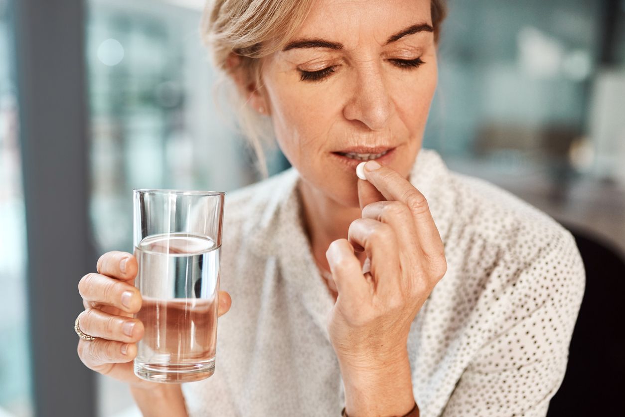 Shot of a mature businesswoman taking medication in an office