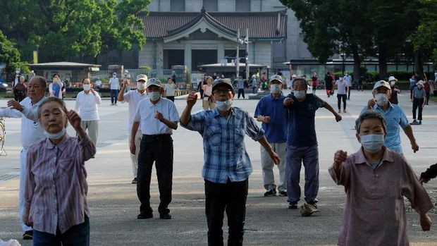 This picture taken on May 25, 2021 shows people taking part in a morning 'radio taiso' exercise at a park in Tokyo. - It might not make the cut for Olympians at Tokyo 2020, but each day in Japan's parks, schools and offices millions perform the country's most popular stretching routine: radio taiso. (Photo by Kazuhiro NOGI / AFP) / TO GO WITH Oly-2020-2021-Japan-health-exercise-virus-taiso,FOCUS by Ayaka McGill and Katie Forster